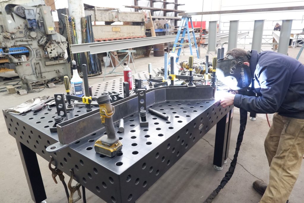 Sparks fly as an expert welder works at the work the table in the C G Fabrication shop.
