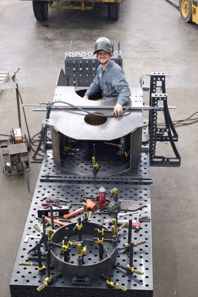 A CGF employee looks up from his welding project with a friendly smile. The team is positive and energized.