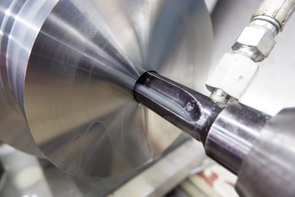 Boring bit drills through a solid metal cylinder.