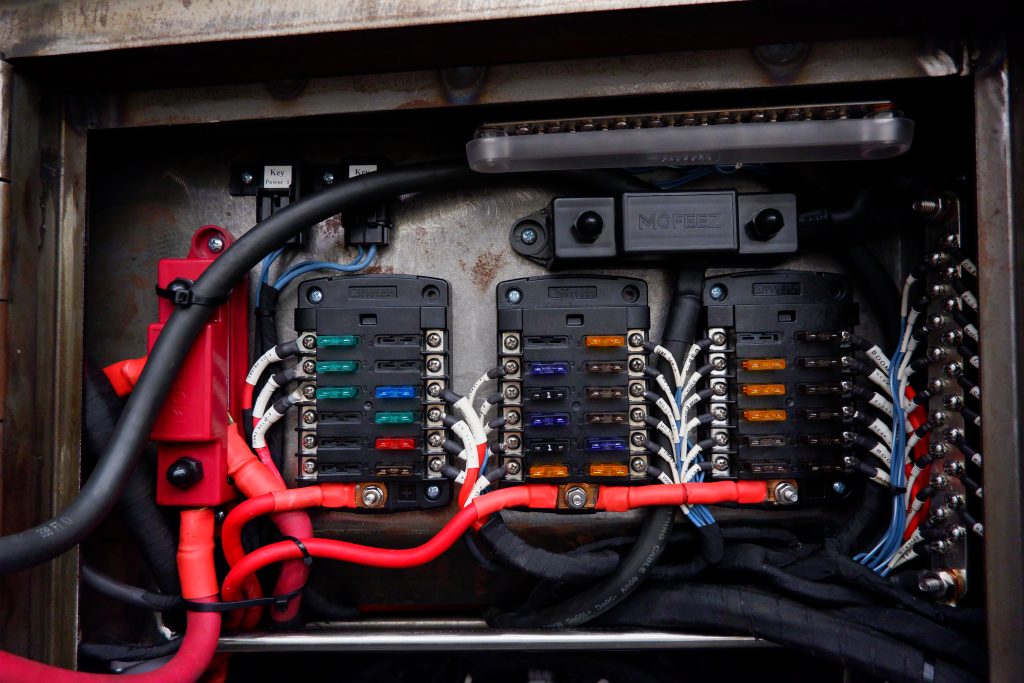 Professional off-road vehicle fuse panel installation with labeled auxiliary circuits and heavy-duty wiring
